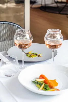 a table with two glasses of wine and a plate of food at La Prévôté - Luxury Chambres d'hôtes & Gastronomic Restaurant in LʼIsle-sur-la-Sorgue