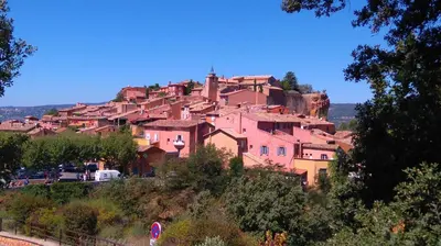 a village on top of a hill with pink houses at Les Vallons Holiday Home in Lioux