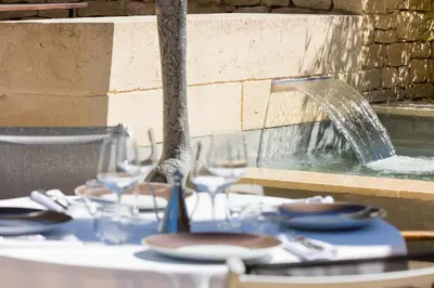 a table topped with glasses and a fountain at Hôtel Carcarille Restaurant Le C in Gordes