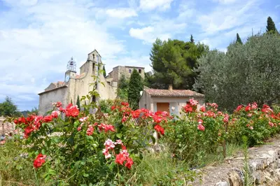 an old building with flowers in front of it at Cabanons Jour & Nuit in Mazan