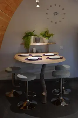 a table with stools in a room with a clock on the wall at Cabanons Jour & Nuit in Mazan