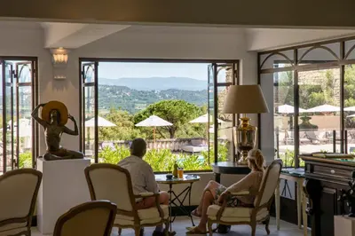 a man and woman sitting in chairs in a living room with a view at Le Phébus & Spa – Relais & Châteaux in Joucas