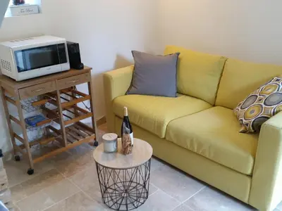 a living room with a yellow couch and a microwave at L'Orgalière Alpilles in Orgon