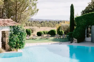 a swimming pool in a garden with chairs and trees at Le Mas De La Rose - Teritoria in Orgon