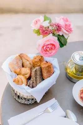 a basket of pastries and a vase of pink roses at Le Mas De La Rose - Teritoria in Orgon