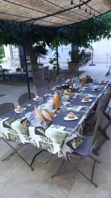 a long table with food on it under an umbrella at Mas des Cigognes in Le Thor