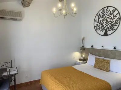 a bedroom with a bed and a clock on the wall at Hotel Les Ambres in Roussillon