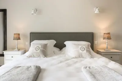 a white bed with white pillows and two lamps at Les Terrasses du Luberon in Bonnieux