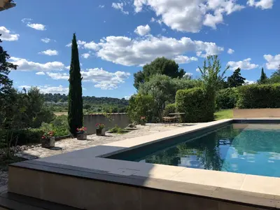 a swimming pool in a garden with a sky background at le Mas des Pignes -adults only in Aix-en-Provence