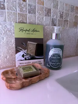 a bathroom counter with a bottle of soap and a box at le Mas des Pignes -adults only in Aix-en-Provence