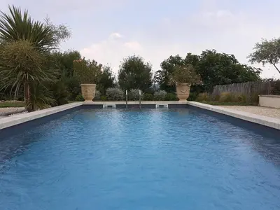 a swimming pool with blue water in a yard at L'ARCHIMBAUDE in Pertuis