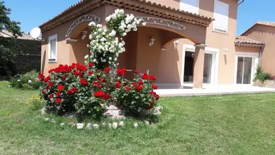 a flower garden in front of a house with red and white flowers at Villa Eglantine in Caumont-sur-Durance