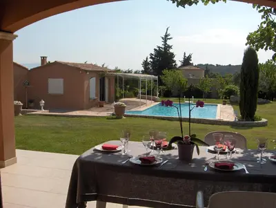 a table with wine glasses on a patio with a pool at Villa Eglantine in Caumont-sur-Durance