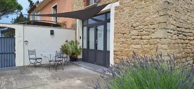 a patio with a table and chairs in front of a building at Gîte Mas de la Restanque in Monteux