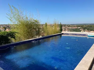 a large blue swimming pool with a view of a city at Belle villa en Provence in Lançon-Provence