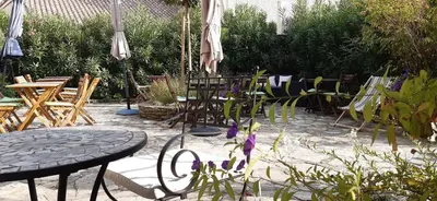 a patio with a table and chairs and an umbrella at Hôtel Le Siècle in Mazan