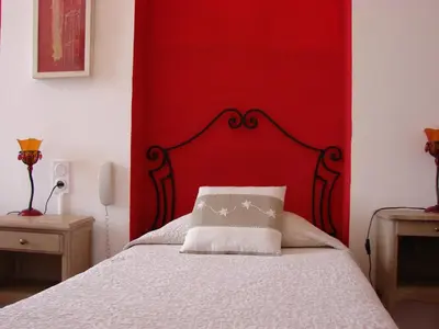 a bedroom with a red headboard and a white bed at Hôtel Le Siècle in Mazan
