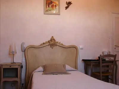 a bedroom with a bed with a wooden head board at Hôtel Le Siècle in Mazan