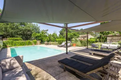a pool with two lounge chairs and an umbrella at Mas Oréa côté piscine in Gordes