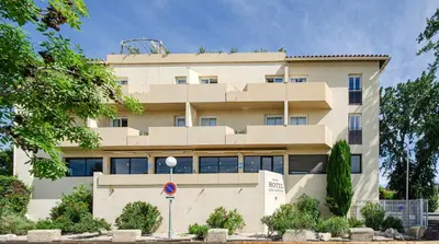 a white building with trees in front of it at Hotel Les Nevons in LʼIsle-sur-la-Sorgue