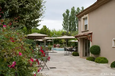 a patio with tables and umbrellas and a pool at Domaine de Mejeans - Teritoria in Alleins