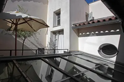 a balcony with an umbrella next to a building at La Maison Sur La Sorgue - Esprit de France in LʼIsle-sur-la-Sorgue