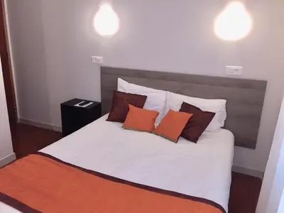a bed with orange and white pillows on it at Hôtel Vendôme in Aix-en-Provence