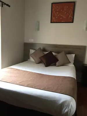a bedroom with a large bed with brown pillows at Hôtel Vendôme in Aix-en-Provence