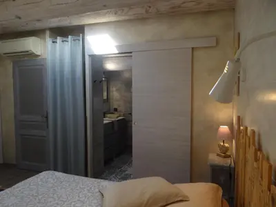 a bedroom with a door leading to a bathroom at Mas Val-Chênaie Gordes in Gordes