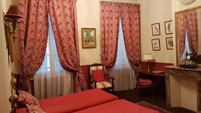 a bedroom with red curtains and a bed and a desk at Hotel Cardinal in Aix-en-Provence