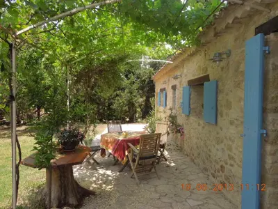 a table and chairs under a tree next to a building at Villa - La Luberonne in Lourmarin