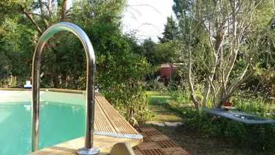 a swimming pool with a wooden bench next to a pool at La Maison de Maïté in Cheval-Blanc