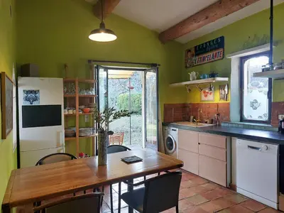 a kitchen with a wooden table and a dining room at Maison d'artiste in Gargas