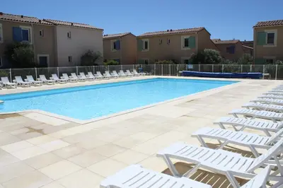 a swimming pool with white lounge chairs and a swimming pool at Charming rental with shared-pool in the Alpilles. in Mouriès