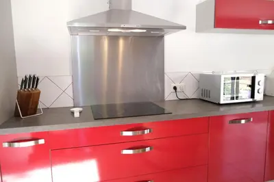 a kitchen with red cabinets and a stove top oven at Nice house with private-pool situated in the heart of the Luberon in Maubec