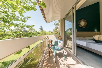 a bedroom with a balcony with a bed and a desk at Belambra Clubs L'Isle Sur La Sorgue - Domaine De Mousquety in LʼIsle-sur-la-Sorgue