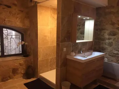 a bathroom with a sink and a tub and a mirror at Le petit trésor du Luberon in Ménerbes
