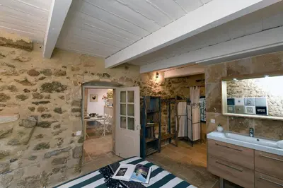 a bathroom with a stone wall and a sink at Le petit trésor du Luberon in Ménerbes
