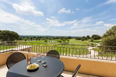 a table with wine glasses on a balcony with a view at Madame Vacances Domaine du Provence Country Club Service Premium in Saumane-de-Vaucluse