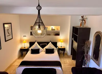 a bedroom with a bed and a chandelier at Le Mas des Mirabelles in Cabannes