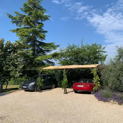 two cars parked under a pavilion in a parking lot at Chambre d'hôtes Le Cèdre in Apt