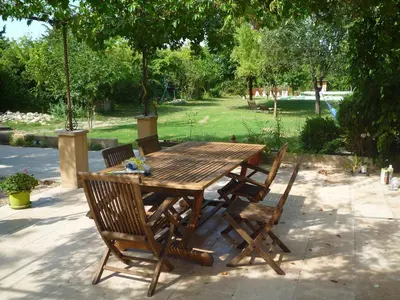 a wooden table and chairs with a park in the background at L'Atelier des Coudelières in Le Thor