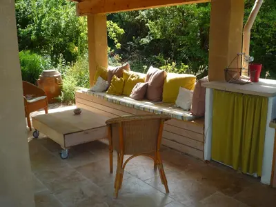 a porch with a couch and two chairs and a table at L'Atelier des Coudelières in Le Thor