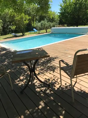 a picnic table and a chair next to a swimming pool at L'Atelier des Coudelières in Le Thor