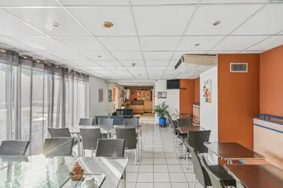 a dining room with tables and chairs and windows at Hôtel AKENA Chateaurenard - Parc des Expositions Avignon in Châteaurenard