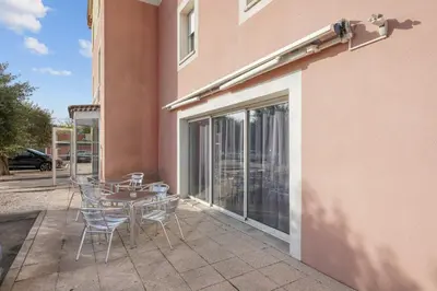 a patio with a table and chairs next to a building at Hôtel AKENA Chateaurenard - Parc des Expositions Avignon in Châteaurenard