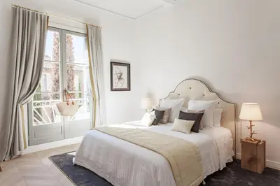 a white bedroom with a large bed and a window at Maison Du Collectionneur in Aix-en-Provence