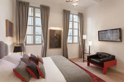 a bedroom with a bed and a chair and windows at Maison Du Collectionneur in Aix-en-Provence
