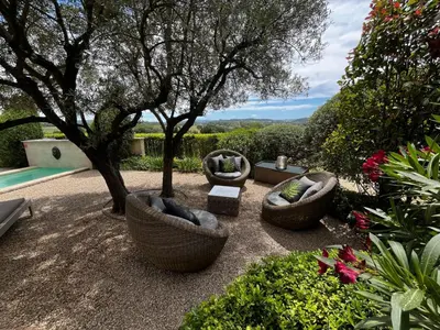 a garden with three chairs and a tree and a pool at Le Mazet d'Emilia avec jardin et piscine privés in Cucuron