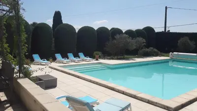 a swimming pool with chairs and a bunch of trees at Le clos des vergers in LʼIsle-sur-la-Sorgue